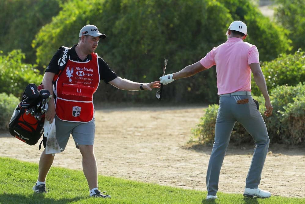Caddy hands a club to golfer