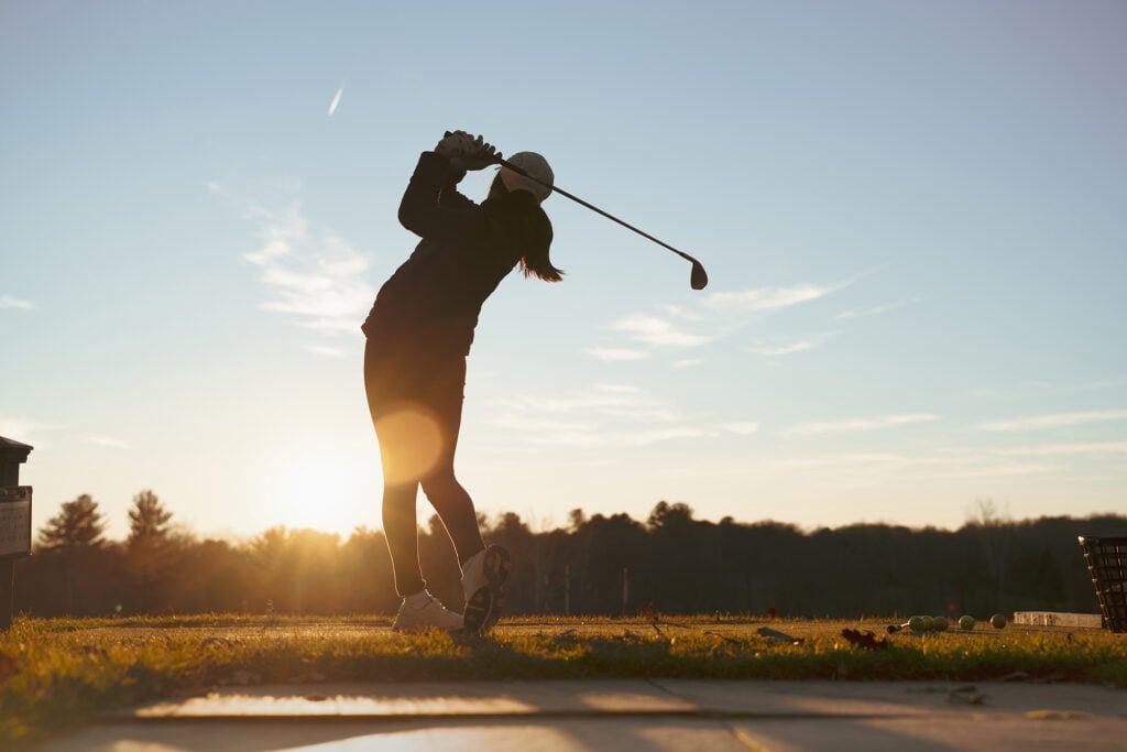 Young junior golfer practicing in a driving range with beautiful sunset light in winter | Source: Adobe