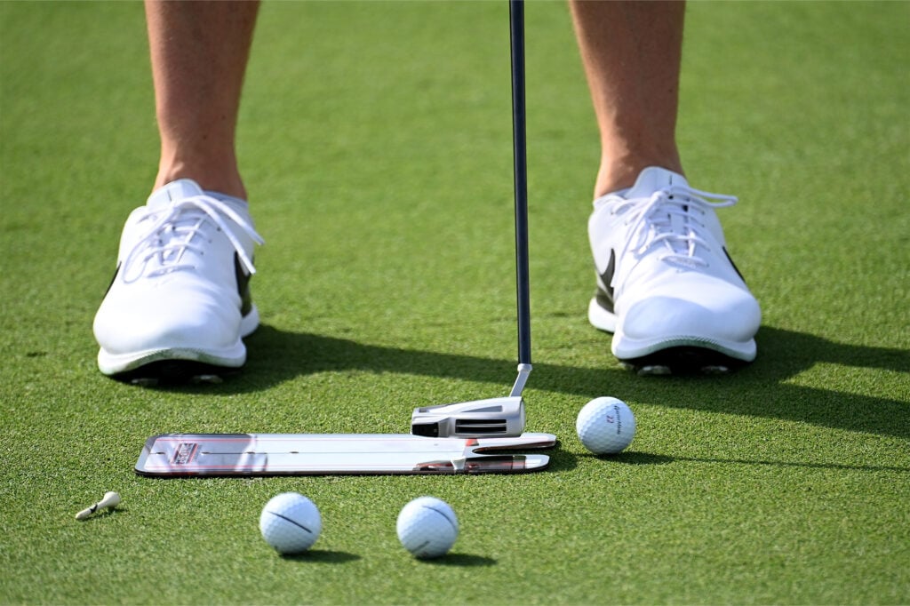 Rory McIlroy practicing his putting with the use of an alignment aid | Source: Getty Images