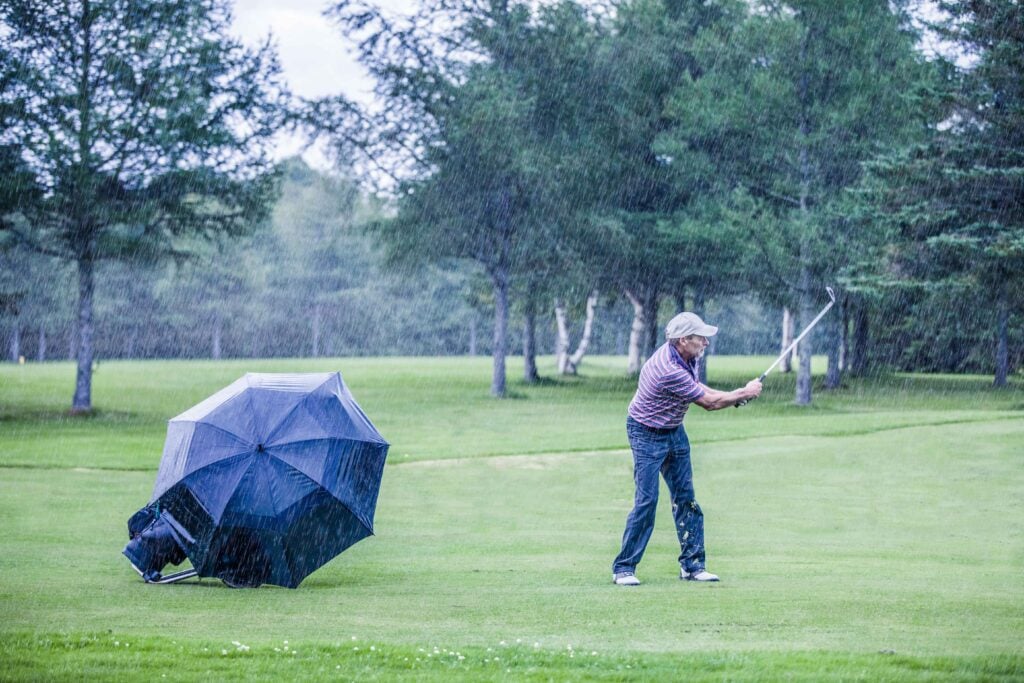 Golfer on a rainy day swingning in the fairway | Credit: Getty Images