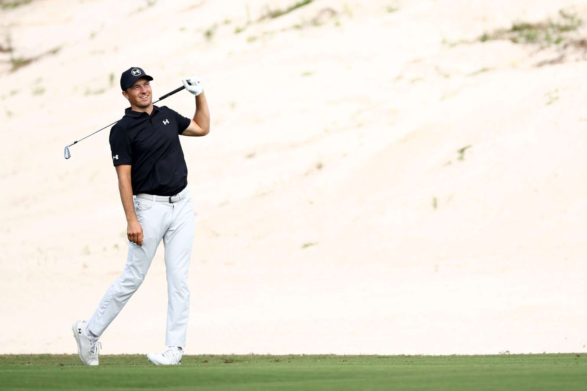 Jordan Spieth walking on a golf course with a club, at the 2025 Hero World Challenge