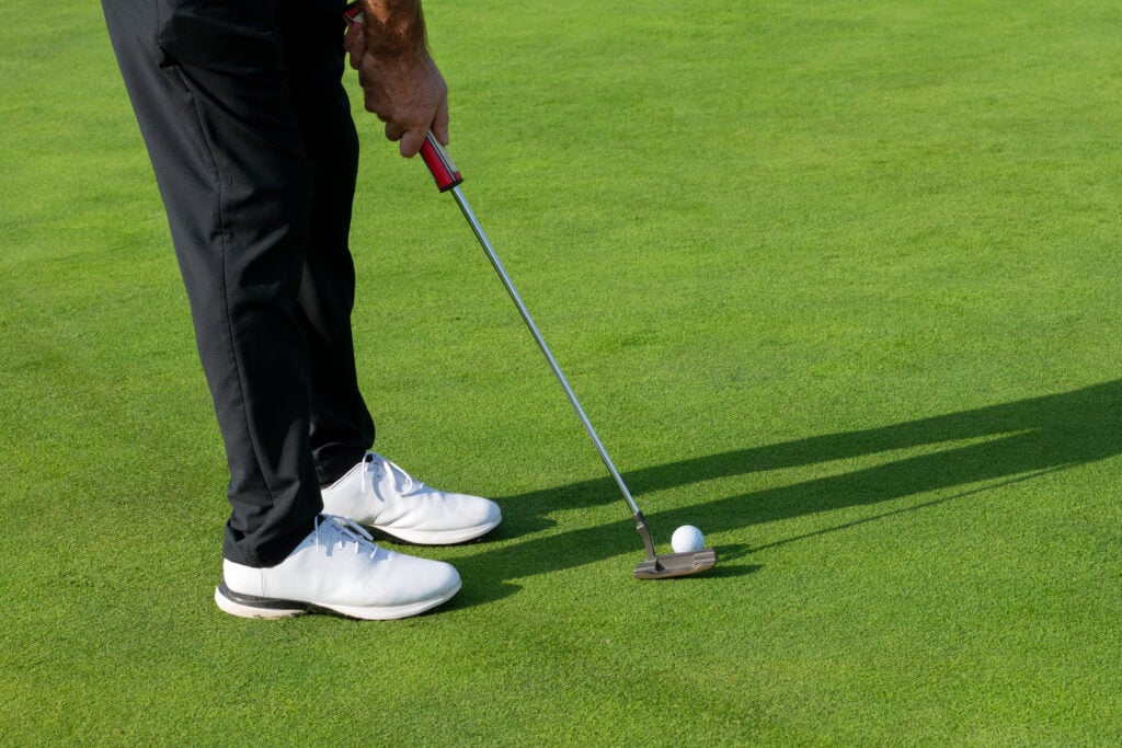 Golfer concentrating on the putting green, about to make a shot | Source: Getty Images