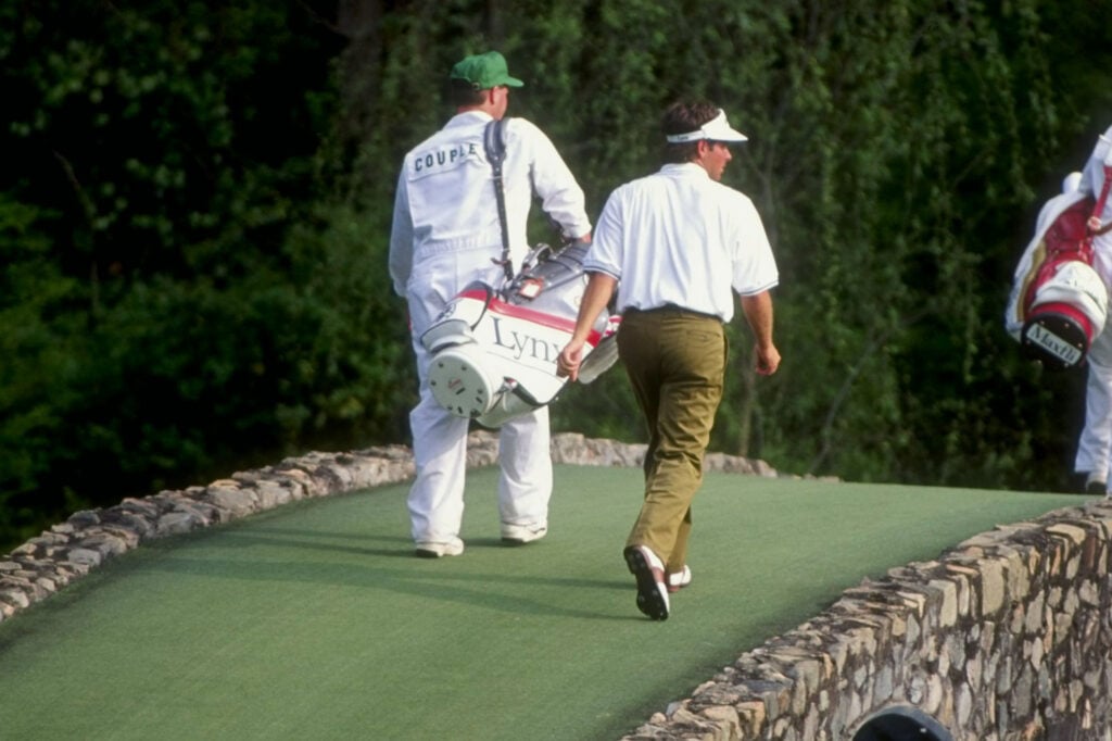 Fred Couples and his caddie walk over a bridge on the 12th hole during the 1992 Masters | Source: Getty