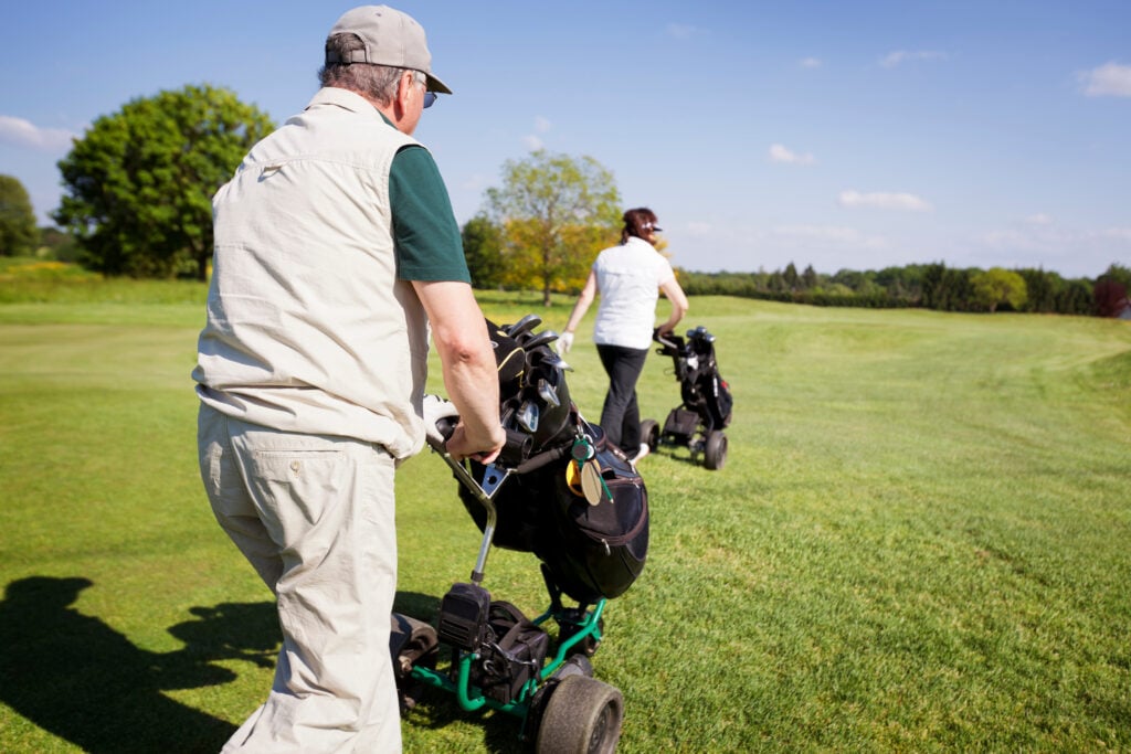 Golfers pushing trolleys on a golf course | Source: Adobe Stock can I get relief if a trolley moves my ball