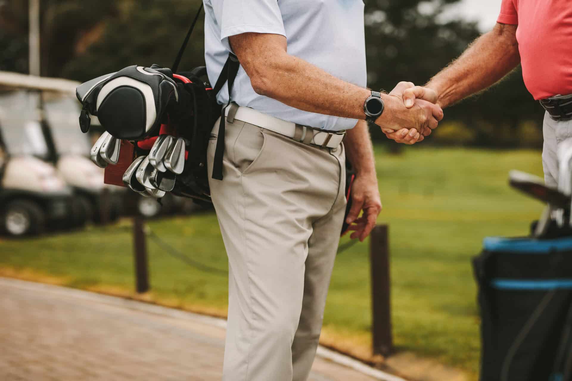 Two golfers shake hands with each other | Source: Adobe Stock